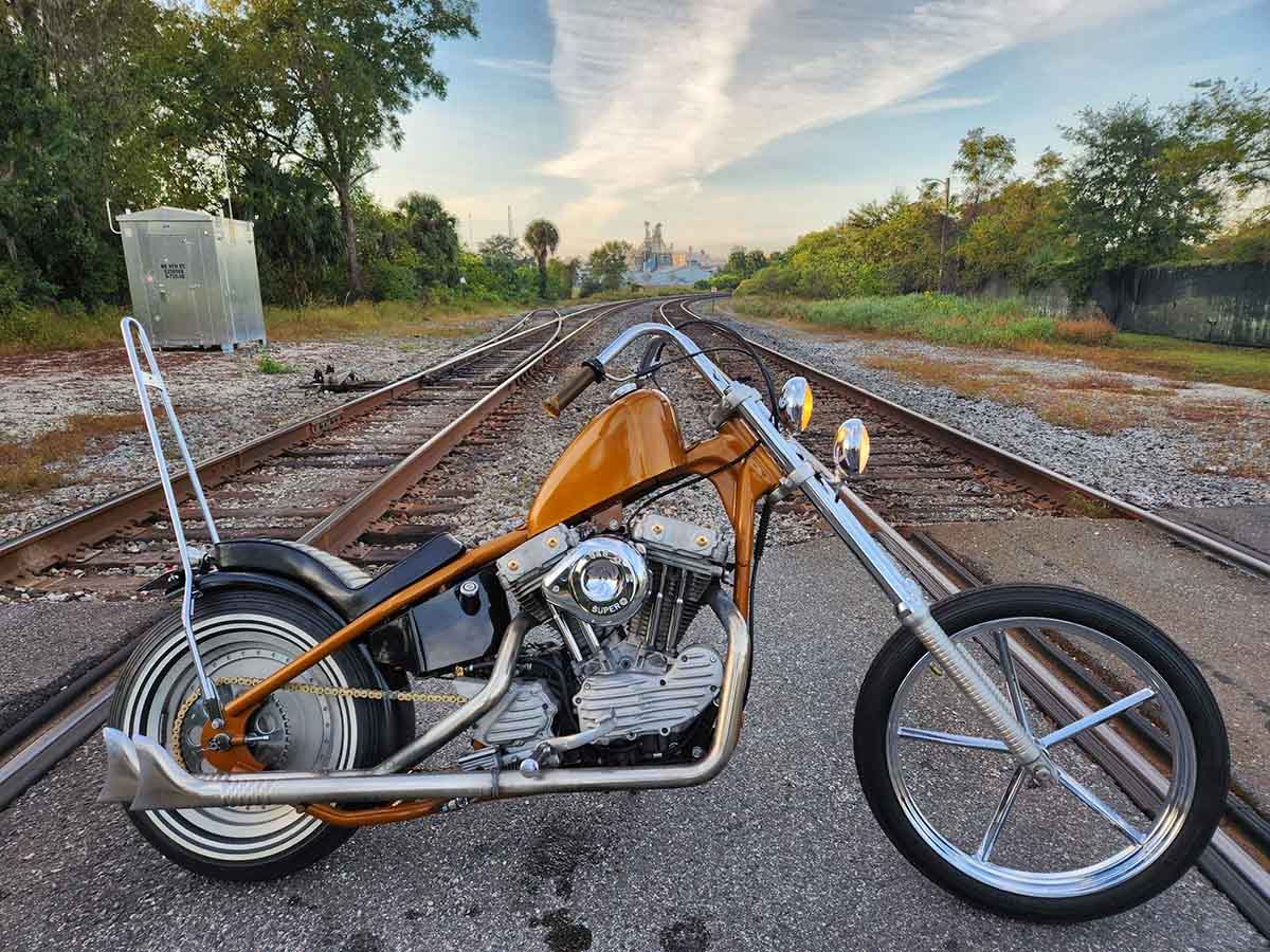 orange sportster chopper in front of railroad tracks